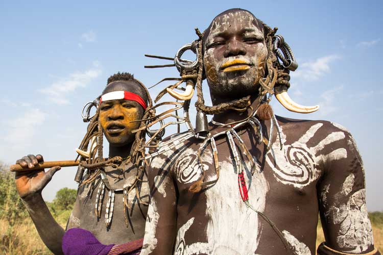 Ethiopia travel image shows Mursi men in South Omo Valley wearing body paint