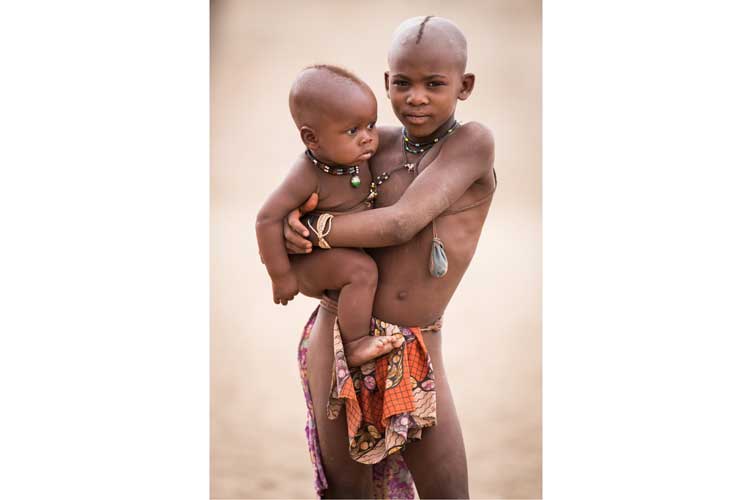 Namibia expedition tour image of Himba boy holding a baby